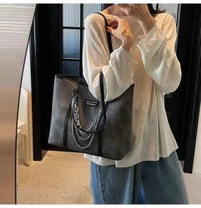 Gros plan du sac fourre-tout gris avec texture mate et chaînes décoratives en argent
