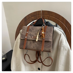 Détail du sac à dos vintage en similicuir marron avec perles en bois et logo en métal