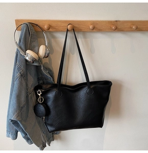 Detail of black leather tote bag with round coin purse and slim shoulder straps