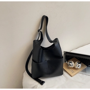 Detail of black pebbled leather bucket bag with large exterior pocket and adjustable strap