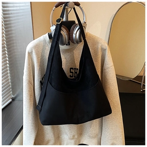 Dettaglio della borsa hobo nera minimalista con tracolla larga e fibbia in oro