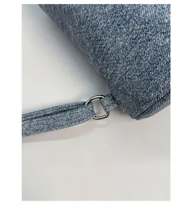 Close-up of blue denim texture bag showing silver D-ring buckle and stitching details