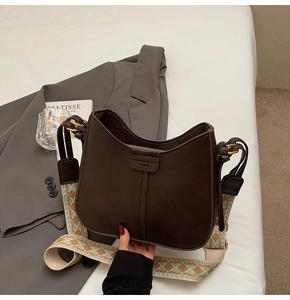 Détail du sac seau en cuir marron foncé avec une bandoulière vintage à motif jacquard