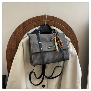Détail du sac à dos vintage gris foncé avec logo métallique et pendentif en perles