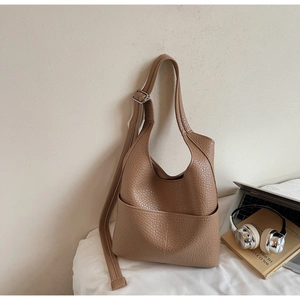 Close-up of brown litchi grain leather hobo bag with adjustable strap and laptop scene