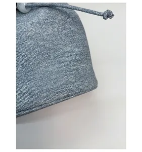 Detail of blue denim fabric texture and drawstring closure with a small bead accent
