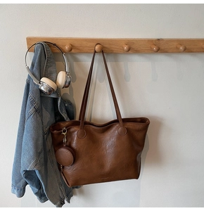 Detail of dark brown leather tote bag with a small matching round coin purse pendant