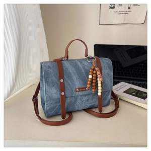 Sac en jean bleu avec lanières en cuir marron et perles en bois vintage sur un bureau