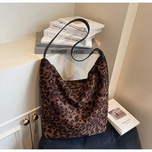 Detail of leopard print hobo bag with suede texture and black leather strap in cozy setting