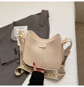 Détail du sac demi-lune blanc cassé avec bandoulière jacquard et texture cuir