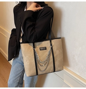 Détail d'un grand sac cabas beige avec des lanières en cuir noir et chaînes argent