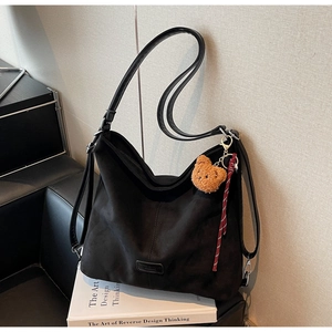 Detail einer schwarzen Hobo-Tasche mit Plüschbär-Anhänger und Leder-Markenetikett