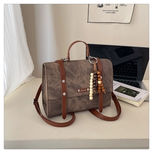 Détail du sac à dos en daim marron foncé avec sangles décoratives et perles en bois