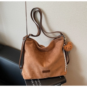 Detailansicht der khakifarbenen Wildledertasche mit Lederriemen und Bärenanhänger