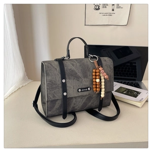Détail du sac texturé marbre gris avec lanières en cuir noir et breloque bohème