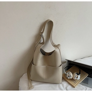 Detail of beige lychee grain leather hobo bag with front pockets and adjustable strap