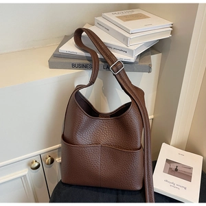 Detail of dark brown pebble leather shoulder bag with side pockets and silver buckle