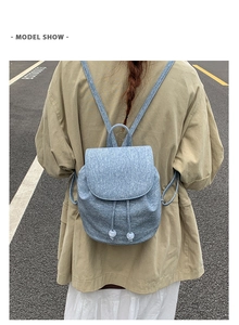Detail shot of light blue textured mini backpack with drawstring and white pompom charms