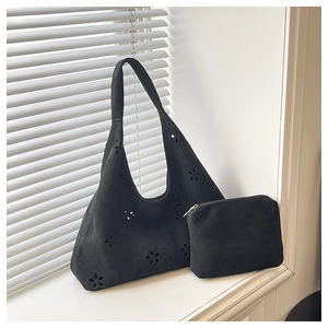 Détail du cabas noir mat avec motif floral découpé au laser et pochette assortie