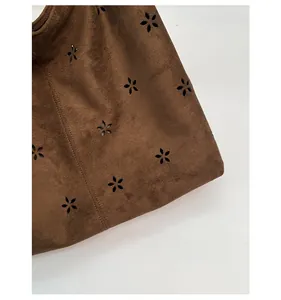 Detail of dark brown suede tote featuring intricate laser-cut floral hollow patterns