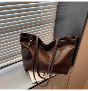 Detail of deep brown tote bag with vintage texture and circular coin purse attachment