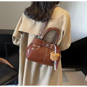 Detail of vintage brown leather bag with silver twist lock and cute plush bear charm