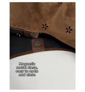 Close-up of magnetic clasp and laser-cut floral patterns on brown suede tote bag