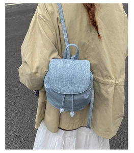 Detail of light blue denim mini backpack with drawstring and beads worn by a model