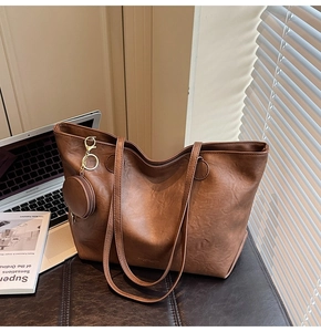 Close-up of brown faux leather tote bag with vintage texture and golden logo detail