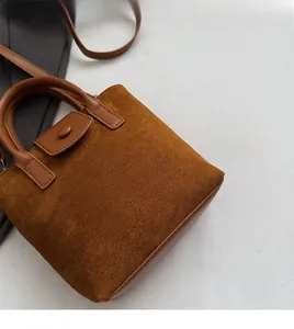 Top view of brown suede bucket bag featuring leather handles and snap button closure detail