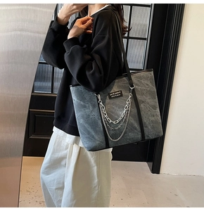 Détail du sac cabas effet marbre gris avec chaînes, porté à l'épaule en vue de profil
