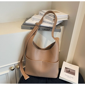 Detail of camel lychee textured hobo shoulder bag with pocket on a minimalist background