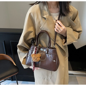 Detail of vintage brown leather handbag featuring contrast stitching and plush bear charm