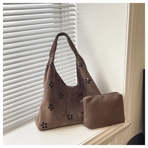 Détail du cabas en daim marron avec motifs floraux découpés au laser et pochette