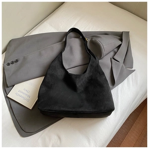 Dettaglio macro della borsa tote in pelle scamosciata nera con fibbia dorata minimale