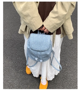Detail of light blue denim texture backpack with drawstring and white sphere accents
