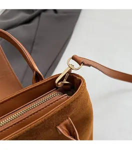 Close-up of premium golden metal hardware and brown suede texture on the handbag