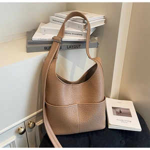 Detail view of khaki brown lychee leather hobo bag with side pockets and silver buckles