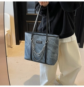 Détail du sac cabas gris vintage avec chaînes en argent punk et étiquette en cuir mode
