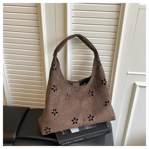 Détails des motifs floraux ajourés sur un grand sac cabas en daim marron foncé