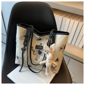 Dettaglio della borsa tote in tela con stampa floreale e ciondolo a coniglietto su sedia