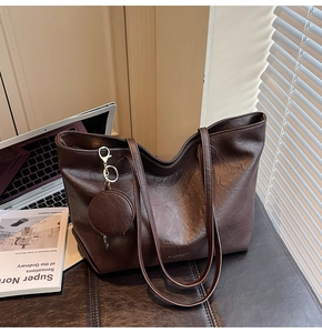 Detail of dark brown tote bag with leather texture and matching coin purse charm