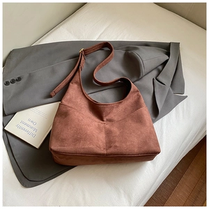 Dettaglio della borsa tote in pelle scamosciata marrone su blazer grigio in stile retrò