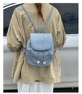 Close-up of light blue textured backpack with drawstring closure and white bead details