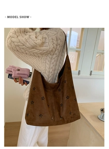 Detailed view of brown suede tote bag with laser-cut hollow floral pattern worn by model