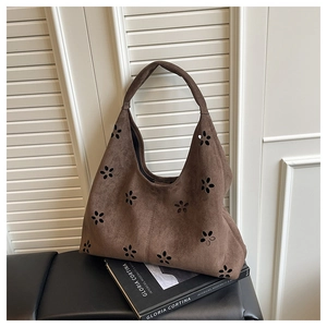 Détail de motifs floraux découpés au laser sur un sac hobo marron foncé en daim