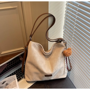 Detail der aprikosenfarbenen Wildledertasche mit braunen Riemen und Teddybär-Anhänger