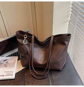 Detail of dark brown tote bag with mini round pouch and golden hardware on side