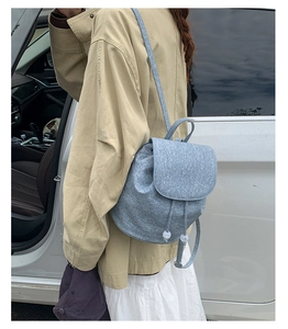 Detail of light blue woven backpack with flap closure and white pearl drawstrings