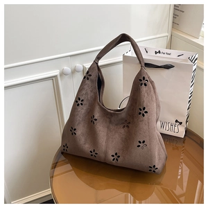 Gros plan des motifs floraux découpés au laser sur le sac hobo en daim marron foncé
